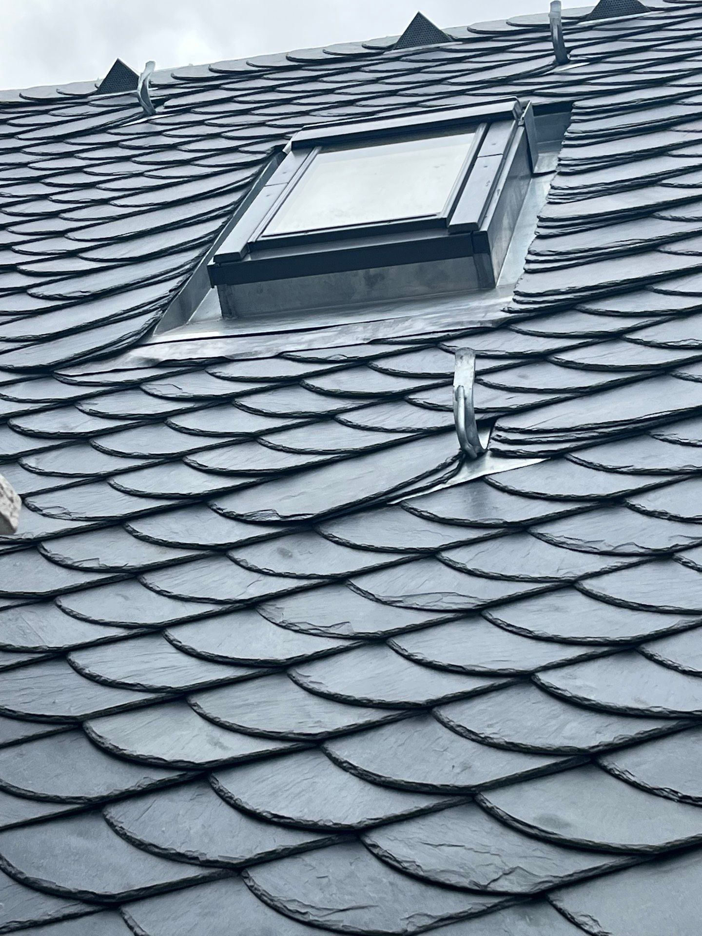 Dunkelgraues Schieferdach mit Oberlicht und Sicherheitshaken.