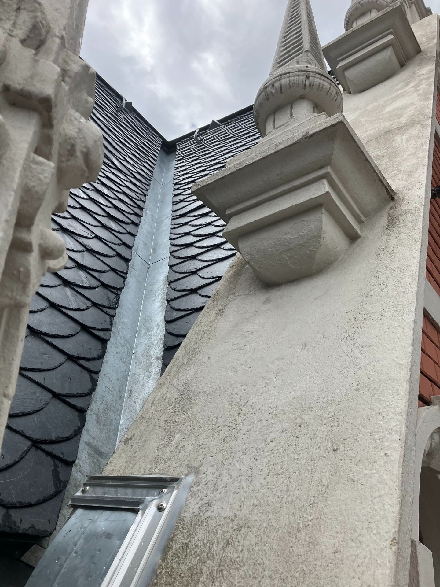 Nahaufnahme der Außenansicht eines Gebäudes mit grauem Schieferdach, weißer Stuckwand und dekorativem Turm.