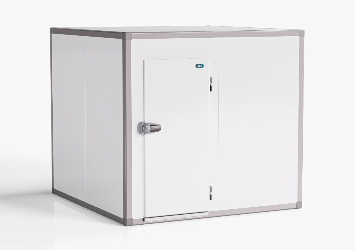 Cámara frigorífica vacía con estantes metálicos y ventiladores de refrigeración, iluminada con luz azul fría.