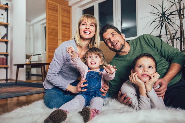 Una familia está sentada en el suelo en una sala de estar.