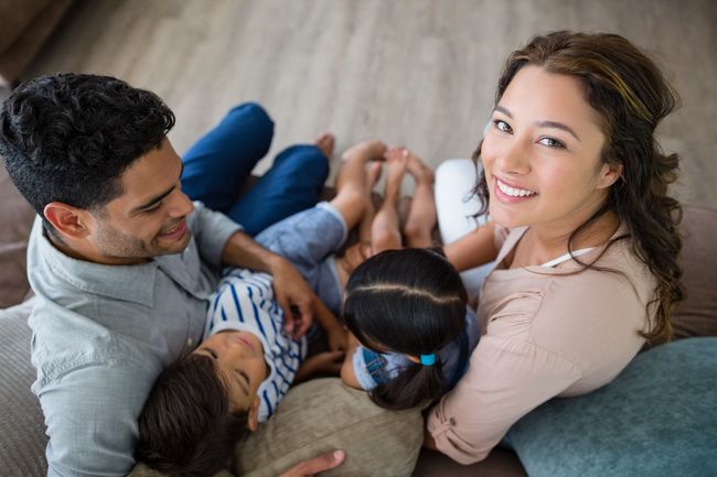 Una familia está sentada en el suelo en un sofá.