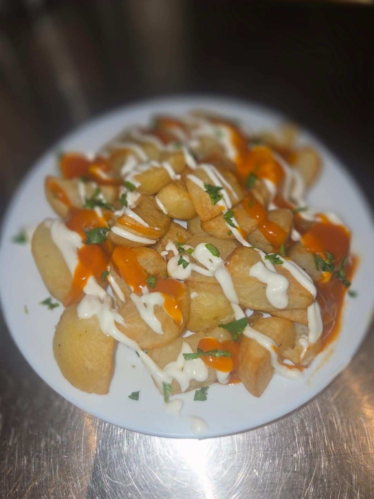 Plato de patatas bravas: patatas fritas rociadas con alioli, salsa picante y perejil.