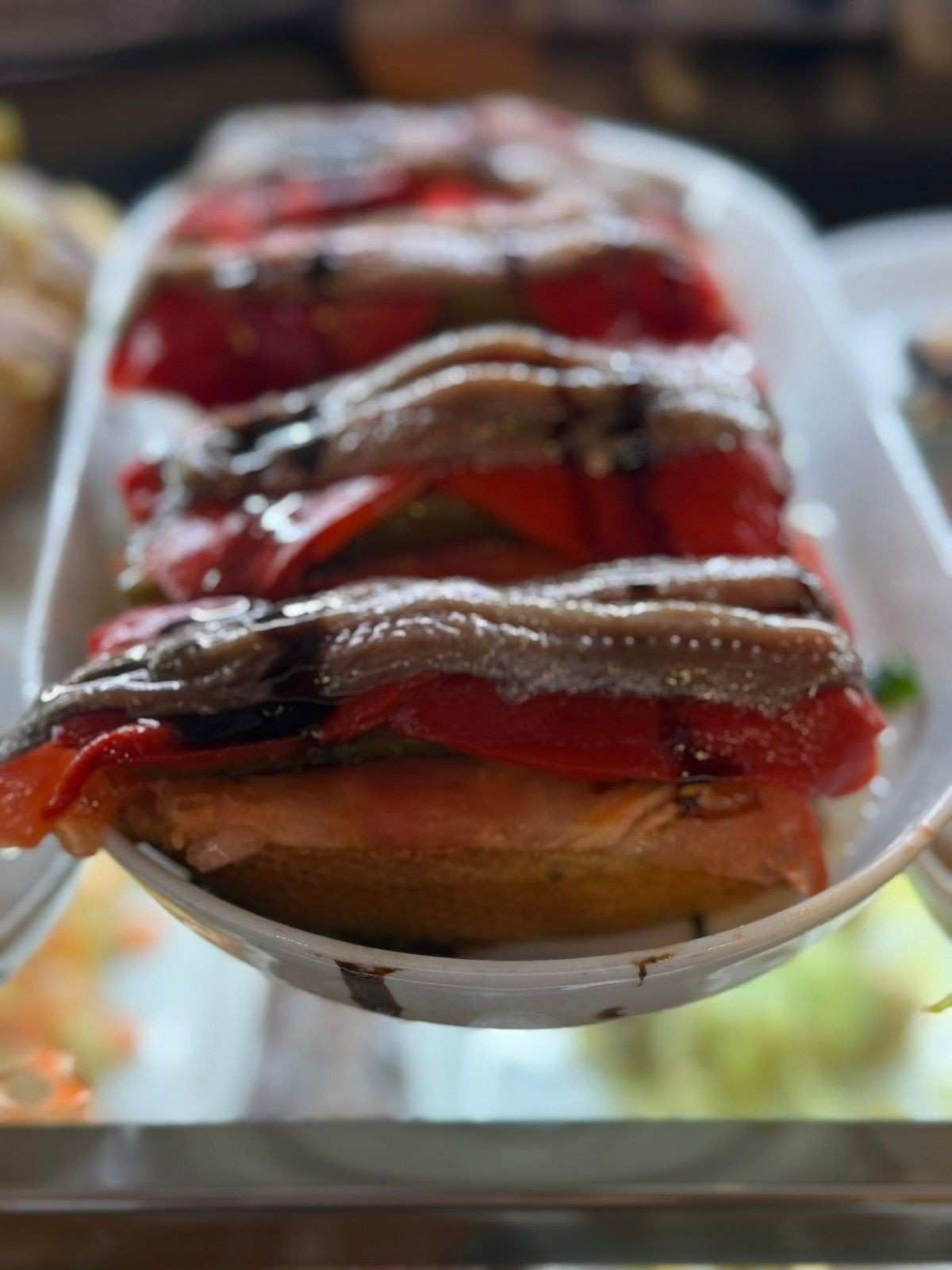 Tostada cubierta con pimientos rojos asados, anchoas y glaseado balsámico.