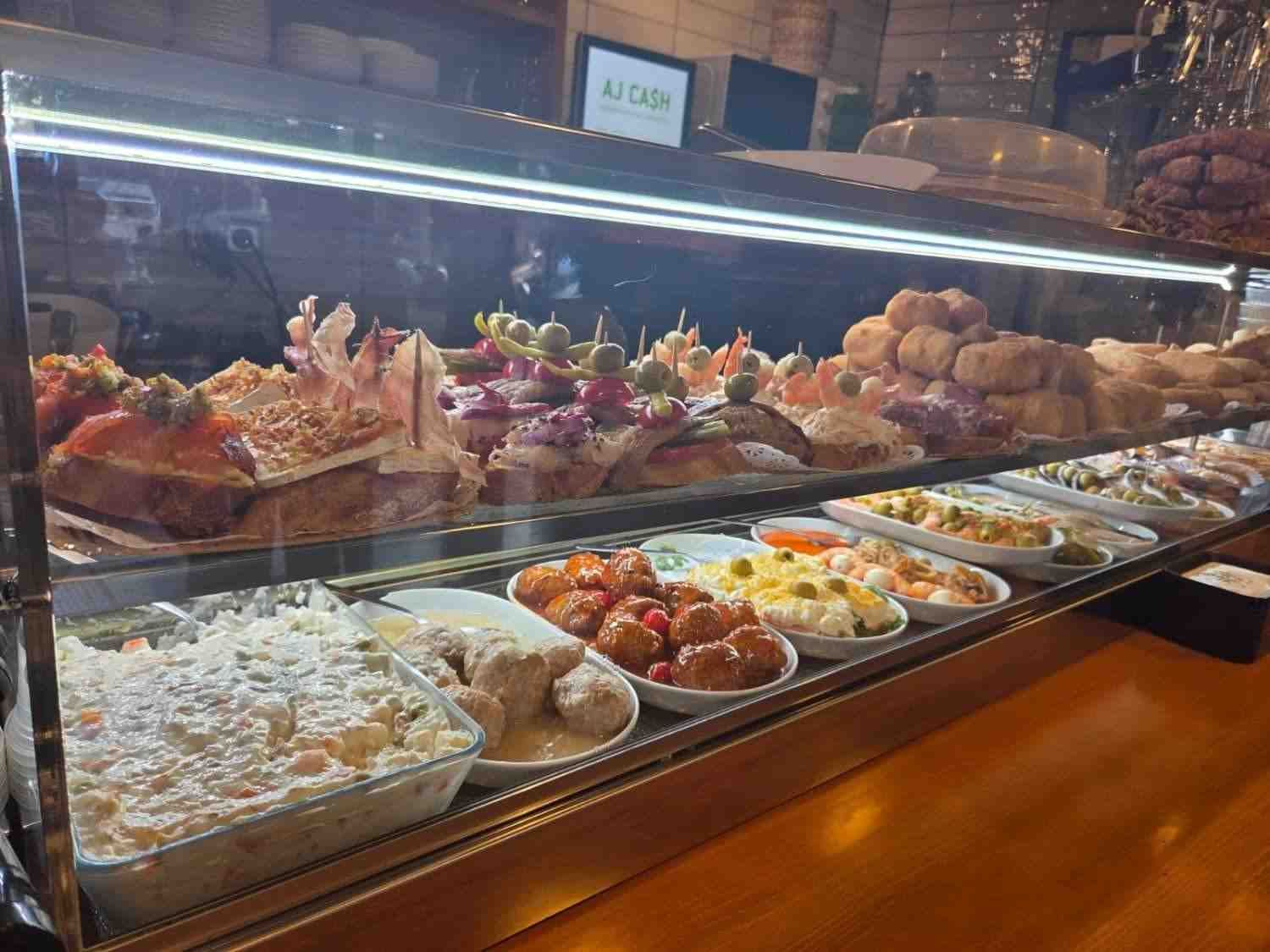 Vitrina repleta de tapas y platos pequeños en un restaurante.