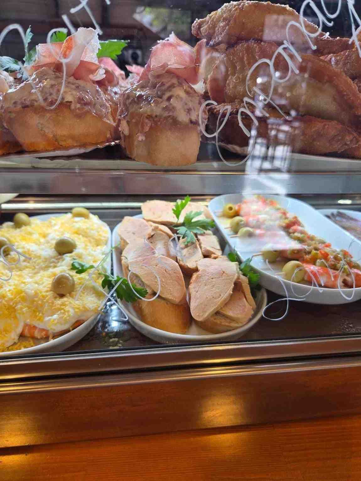 Vitrina con tapas variadas: bocadillos, ensaladas y entrantes rebozados.