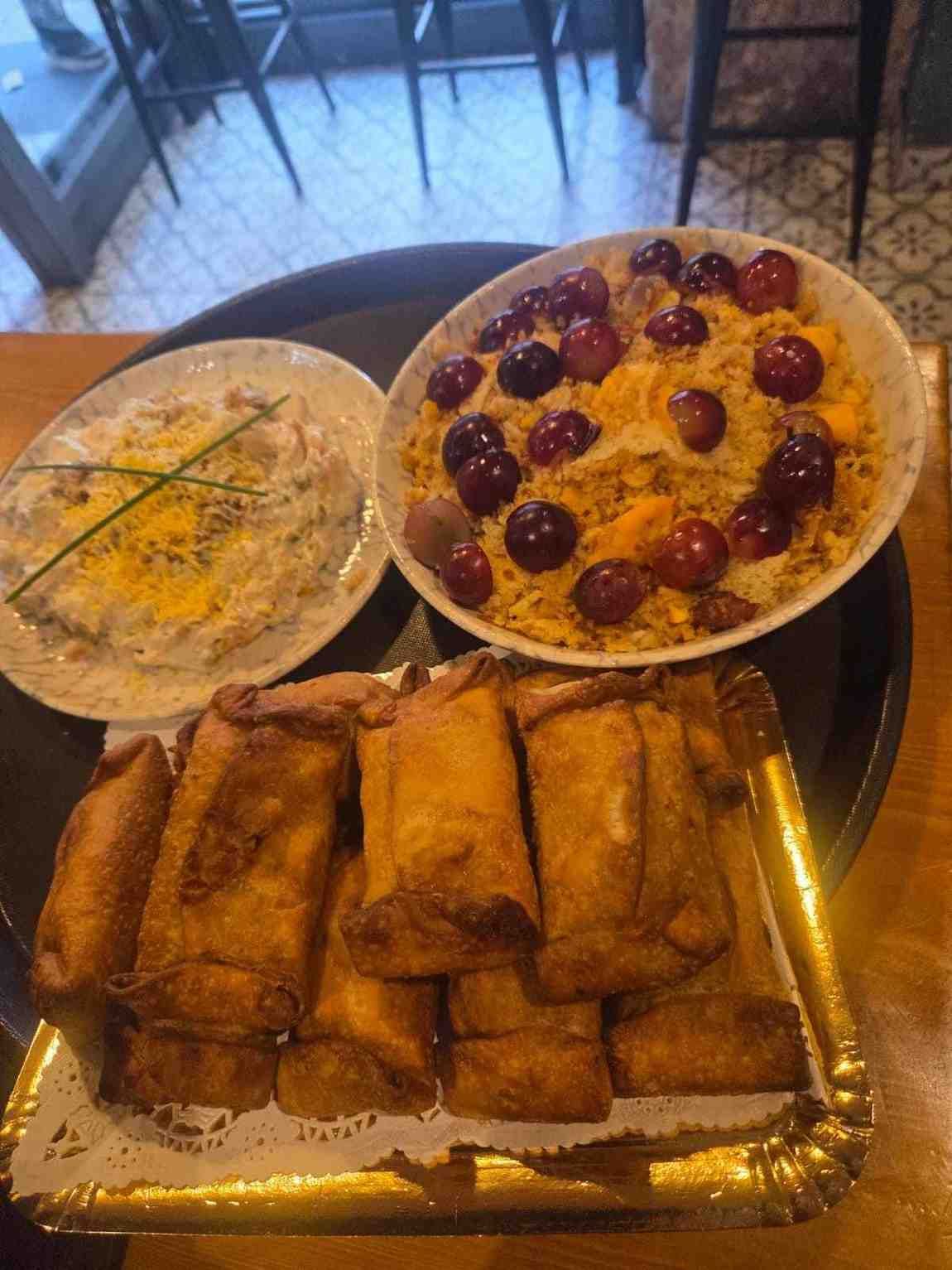 Bandeja de comida variada: rollitos de huevo, plato de arroz con frutas y un plato cremoso.