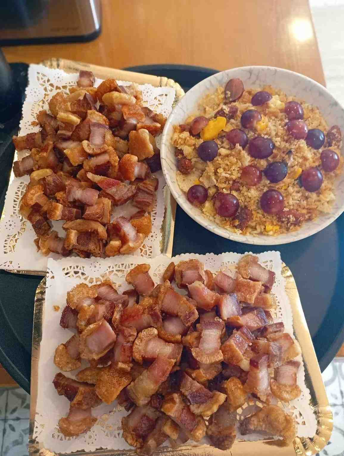 Platos de panceta de cerdo crujiente y un bol de cuscús con uvas, servidos en una bandeja.