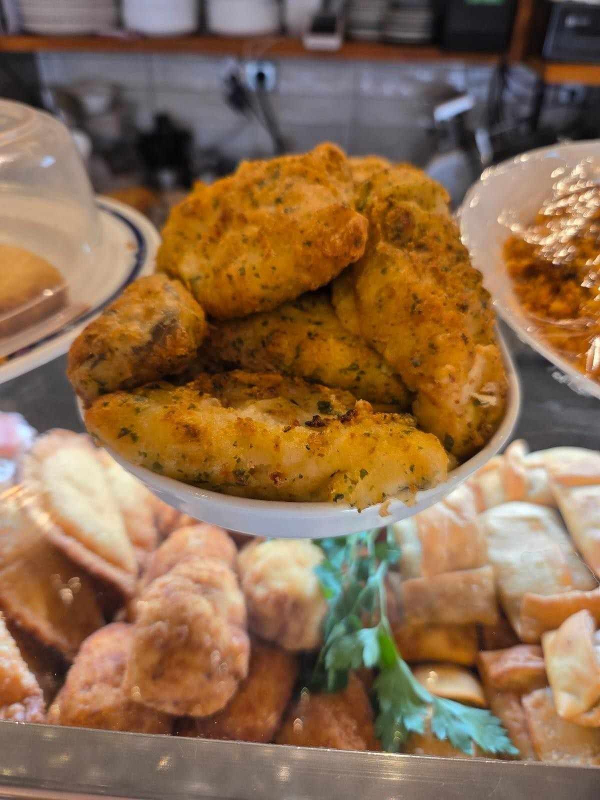 Pollo frito en exhibición en un restaurante junto con otros alimentos.