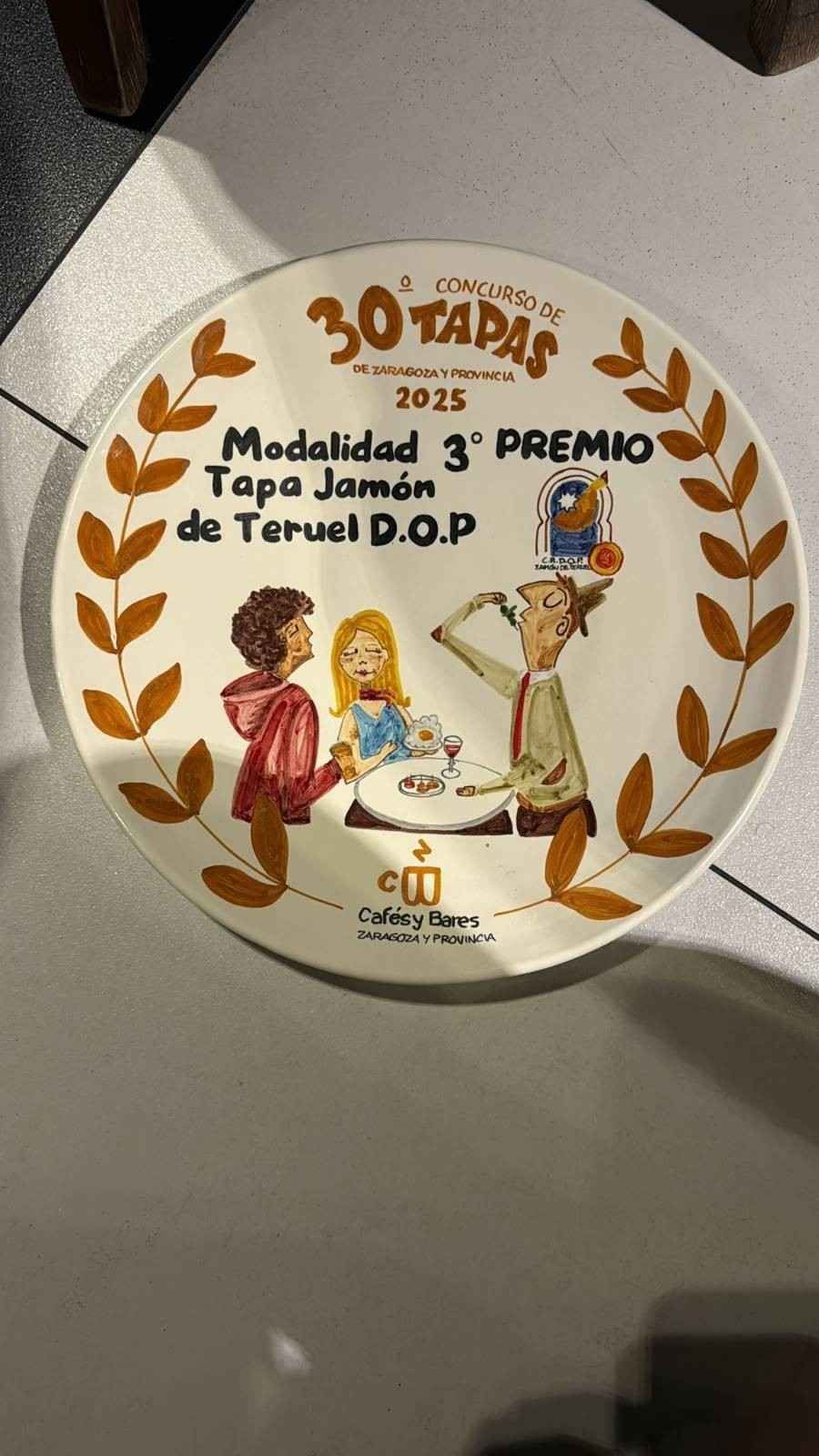 Plato de cerámica con ilustración para un concurso de tapas; la inscripción dice «30 Tapas 2025», «3er Premio» 