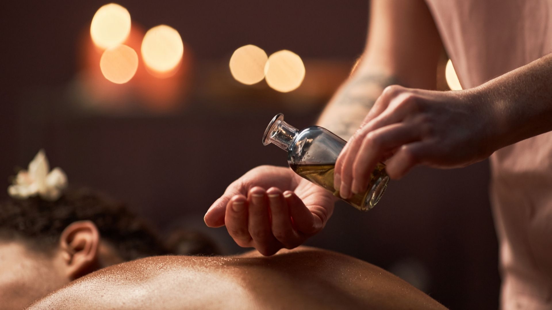 Persona vertiendo aceite sobre la espalda de otra persona durante un masaje.