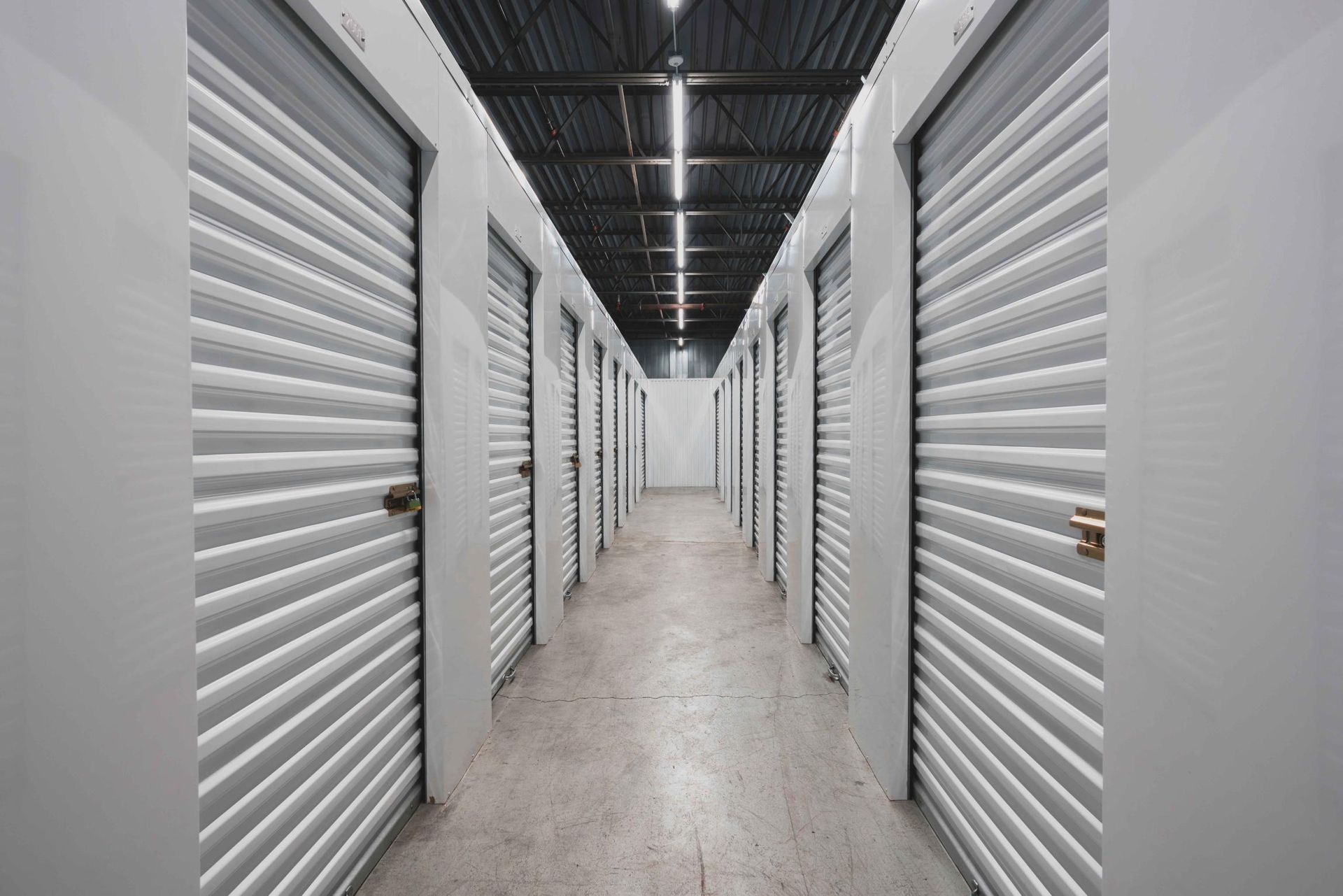 Long couloir bordé de portes blanches de box de stockage dans un centre de self-stockage