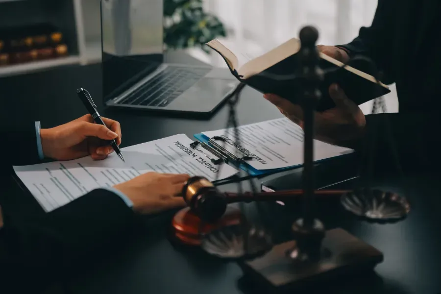 Manos intercambiando bolígrafos sobre documentos en un escritorio durante una reunión de negocios.