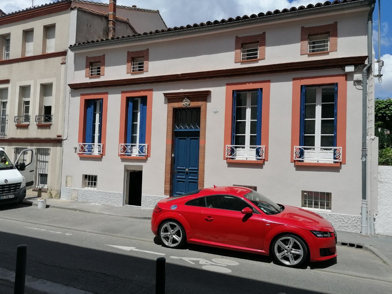 Ravalement de façade à Toulouse avec une voiture rouge devant le bâtiment