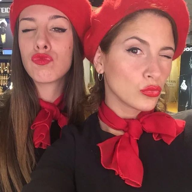 Dos mujeres con sombreros rojos y bufandas posan para una fotografía.