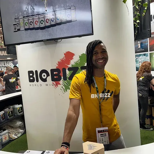 Un hombre con una camisa amarilla está parado frente a un cartel que dice biobizz