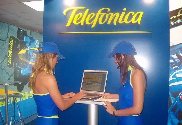 Dos mujeres paradas frente a un cartel que dice telefónica