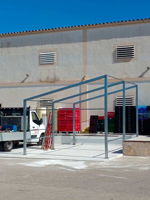 Local comercial industrial al aire libre con marquesina metálica, camión blanco 