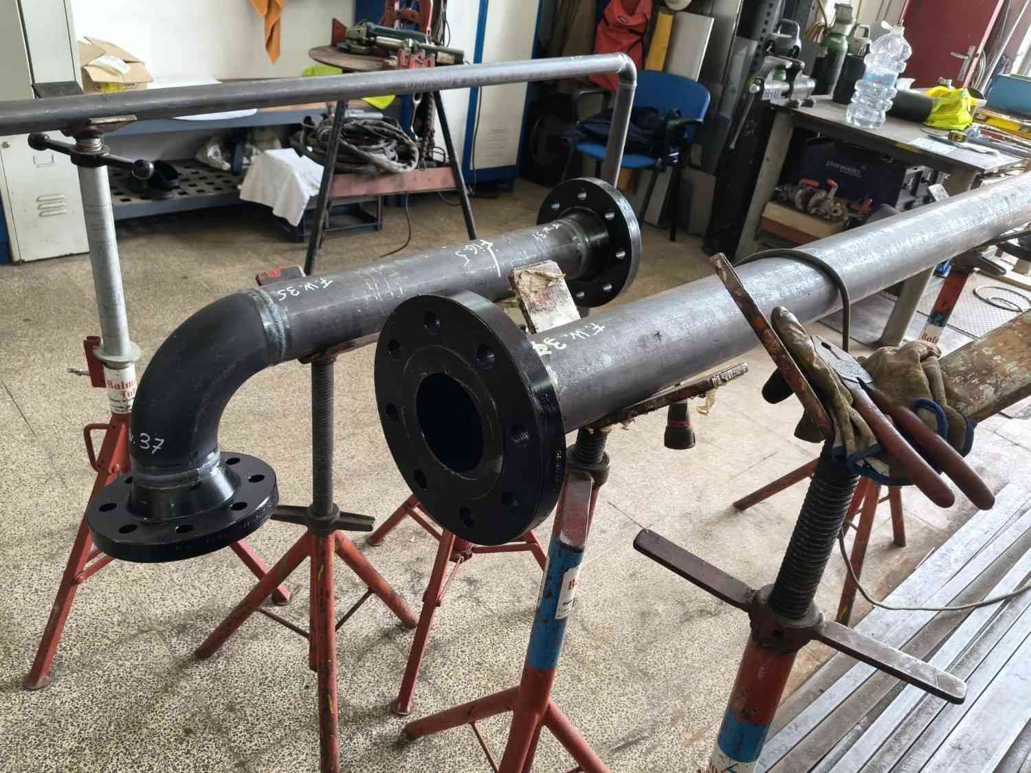 Tubos metálicos industriales con extremos bridados sobre soportes 