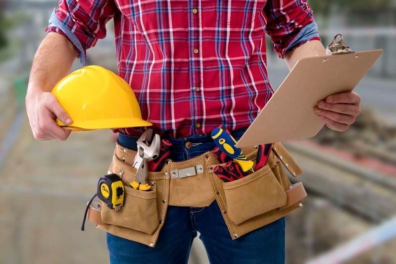 Un trabajador de la construcción lleva un casco y sostiene un portapapeles.