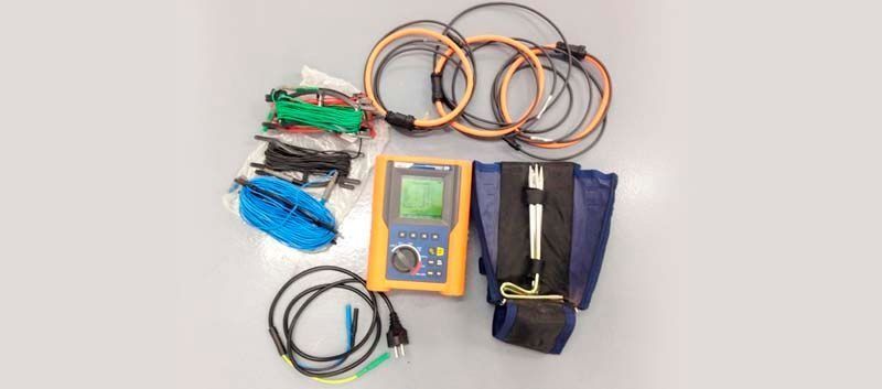 Un montón de cables y un dispositivo están sobre una mesa.