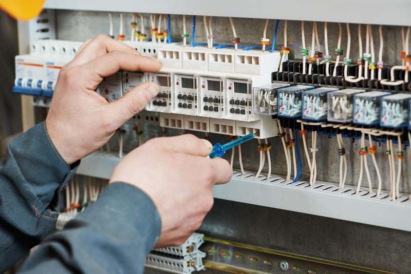 Un hombre está trabajando en un panel eléctrico con un destornillador.