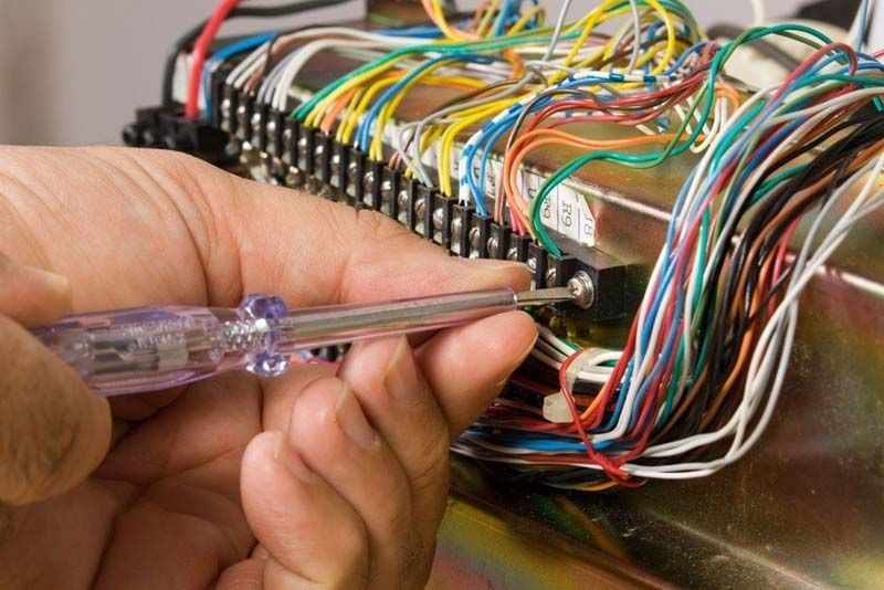 Una persona sostiene un destornillador sobre un montón de cables.