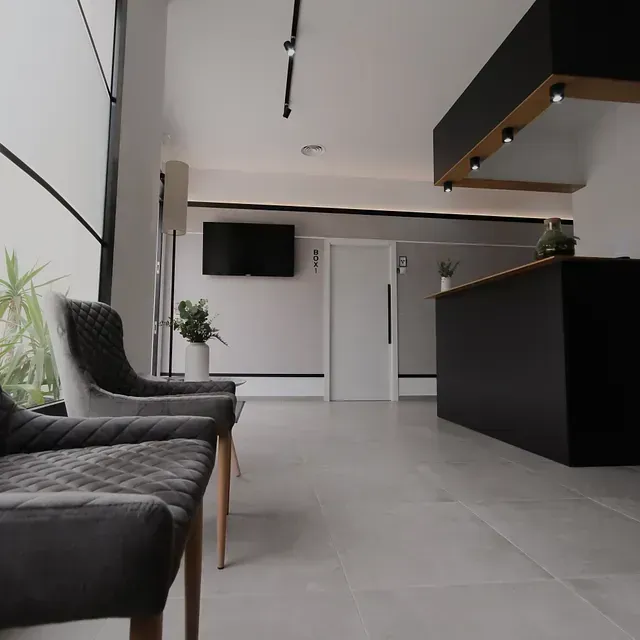 Una sala de espera con sillas y un televisor en la pared.