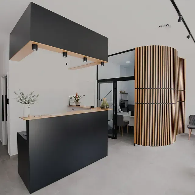 Un área de recepción con un mostrador negro y una pared de madera.