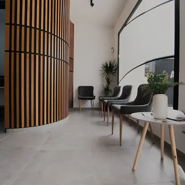 Una sala de espera con sillas y mesas y una pared de madera.