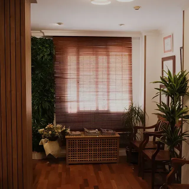 Una sala de estar con una mesa y sillas y una ventana con persianas.