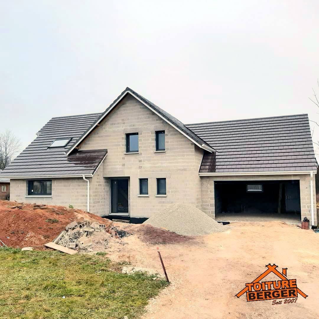 Nouvelle maison beige en construction, avec un toit gris et un garage attenant ; le jardin à l’avant n’est pas encore aménagé