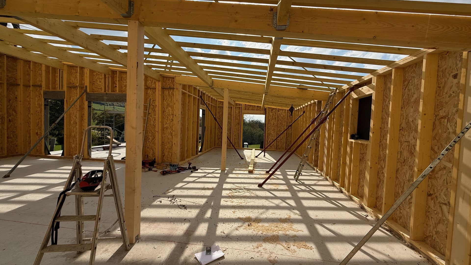 Intérieur d’une maison à ossature bois en construction avec charpente et poutres apparentes