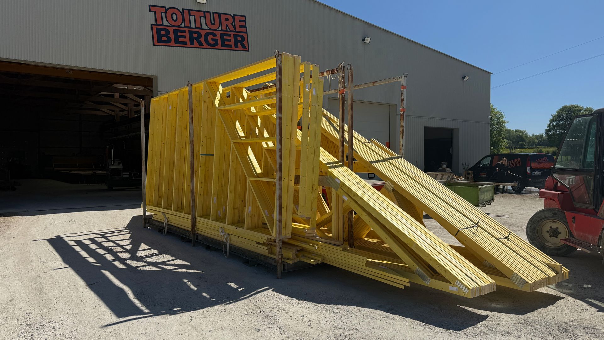 Machine industrielle jaune avec des rampes, à l’extérieur d’un entrepôt, sur un terrain de gravier