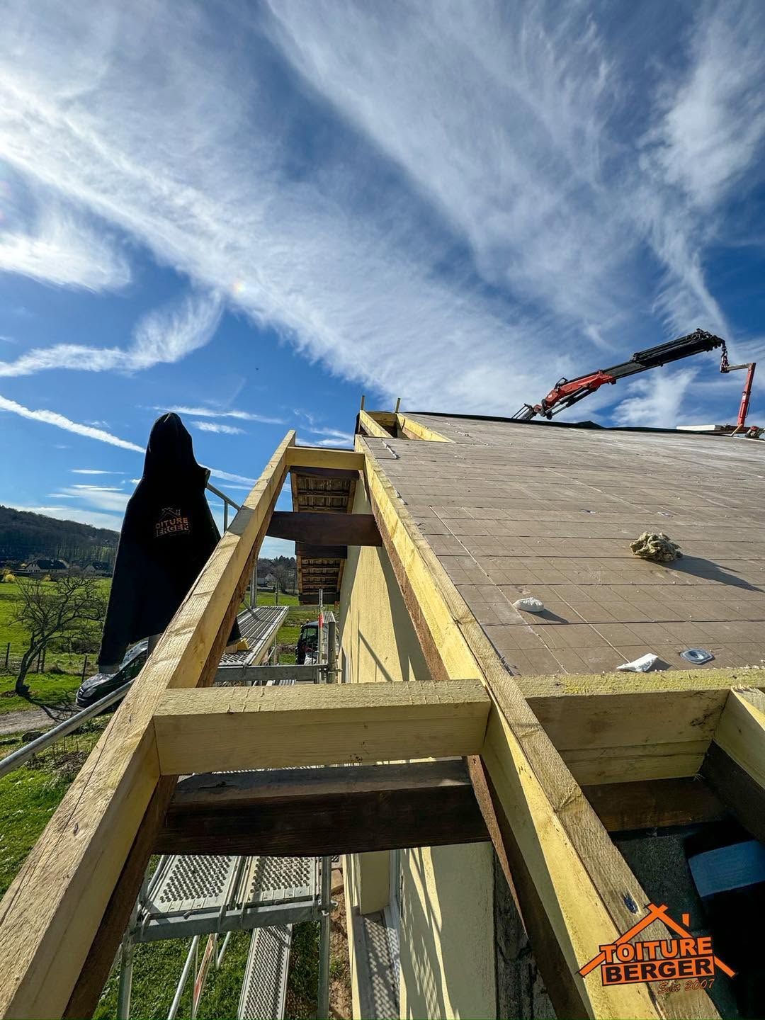Personne sur un toit avec pose de sarking, avec un ciel bleu et une grue en arrière-plan