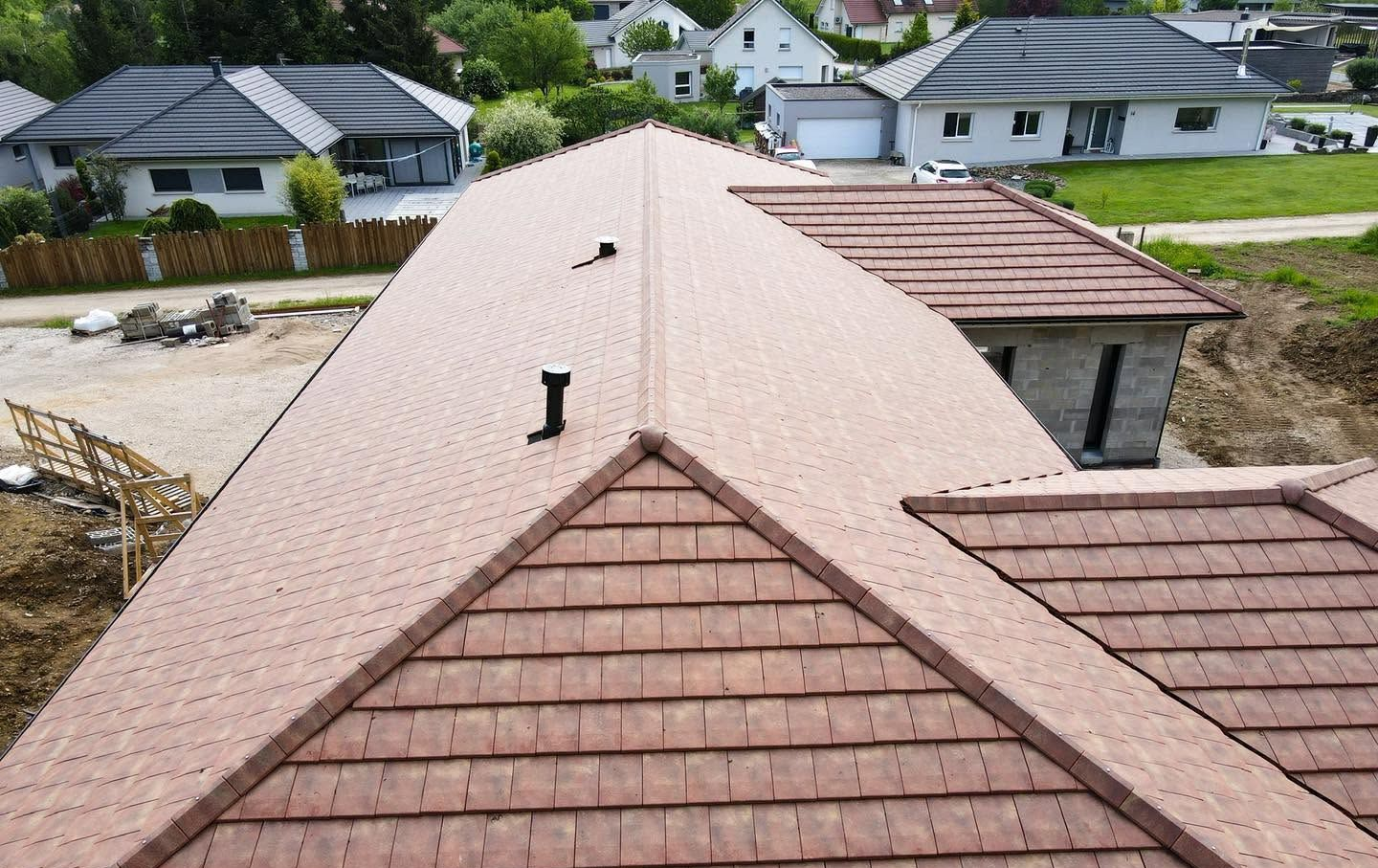 Vue aérienne du toit d’une maison aux bardeaux beige clair et des maisons alentour dans un quartier résidentiel