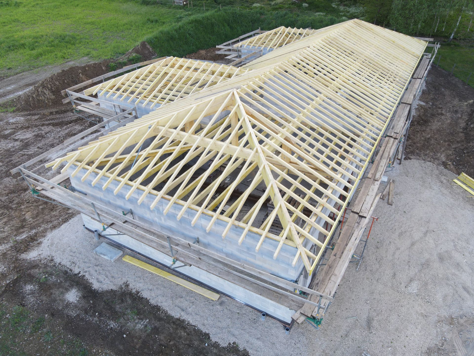 Charpente à fermes posée sur une maison en construction, vue de dessus.