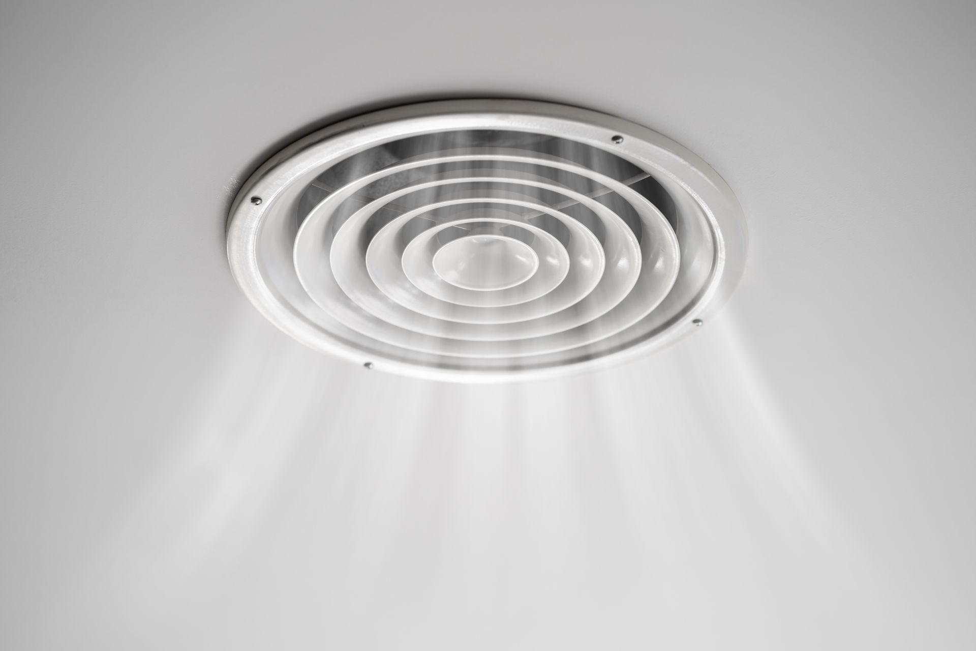 Grille d'aération de plafond à lamelles circulaires, diffusant un flux d'air doux vers le bas.