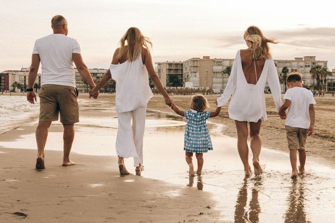 Familie mit Kinder läuft zum Sonnenuntergang am Strand entlang