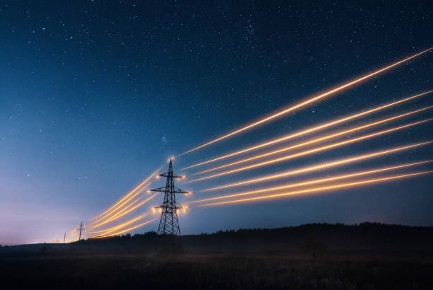Une rangée de lignes électriques traversant un champ la nuit.