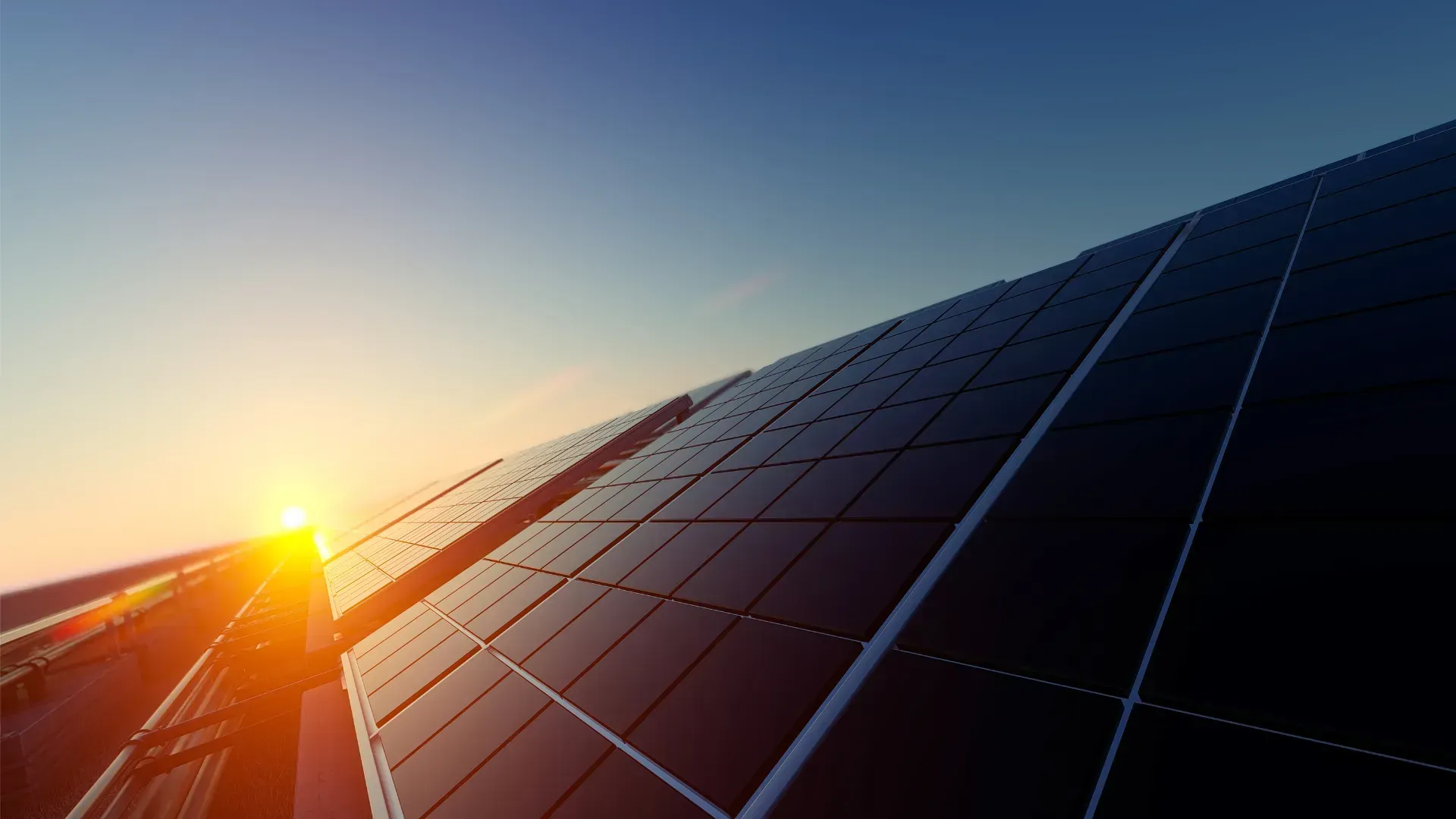 Le soleil se couche derrière une rangée de panneaux solaires.