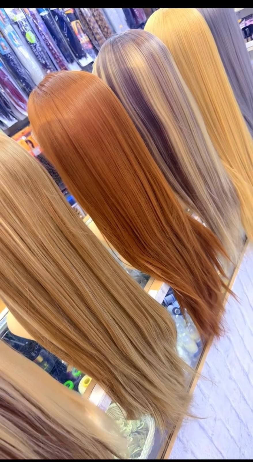 Tres extensiones de cabello largo y liso en rubio, castaño rojizo y plateado exhibidas en un salón.