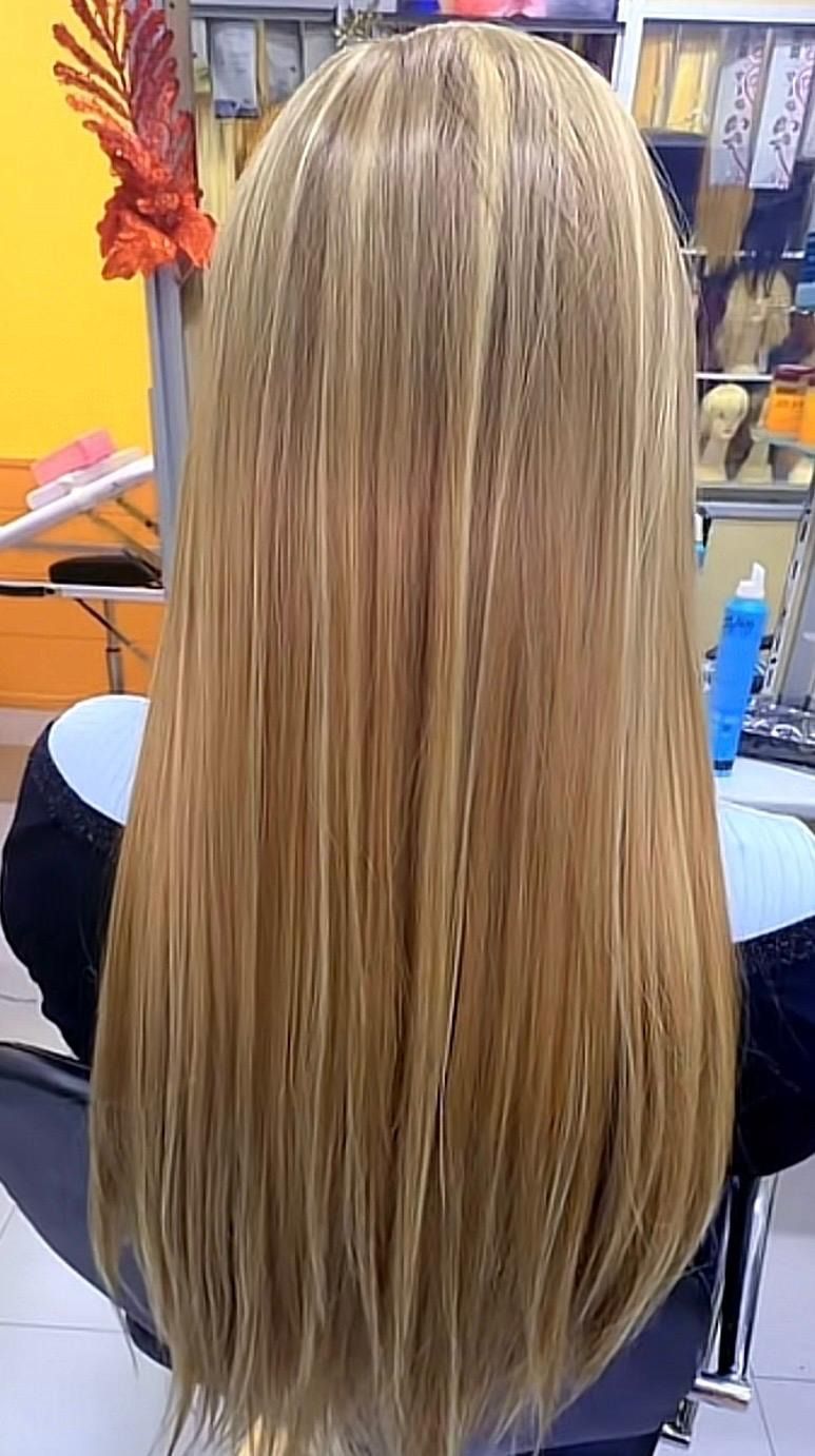 Cabello largo, liso y rubio visto desde atrás en una silla de peluquería.