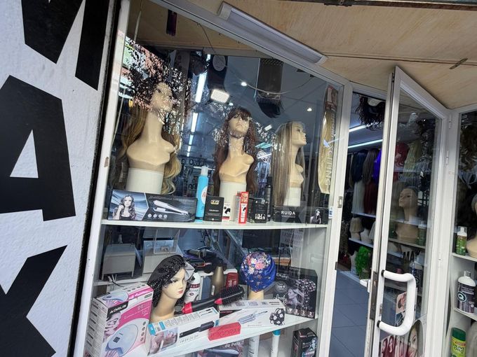 Escaparate con cabezas de maniquí, pelucas y accesorios para el cabello.