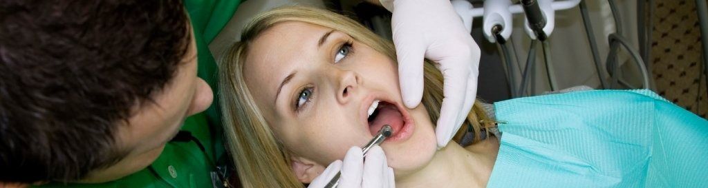 Una mujer está siendo examinada por un dentista.