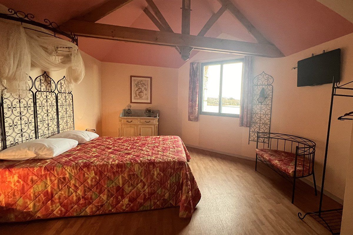 Chambre rouge avec lit double et fenêtre ensoleillée
