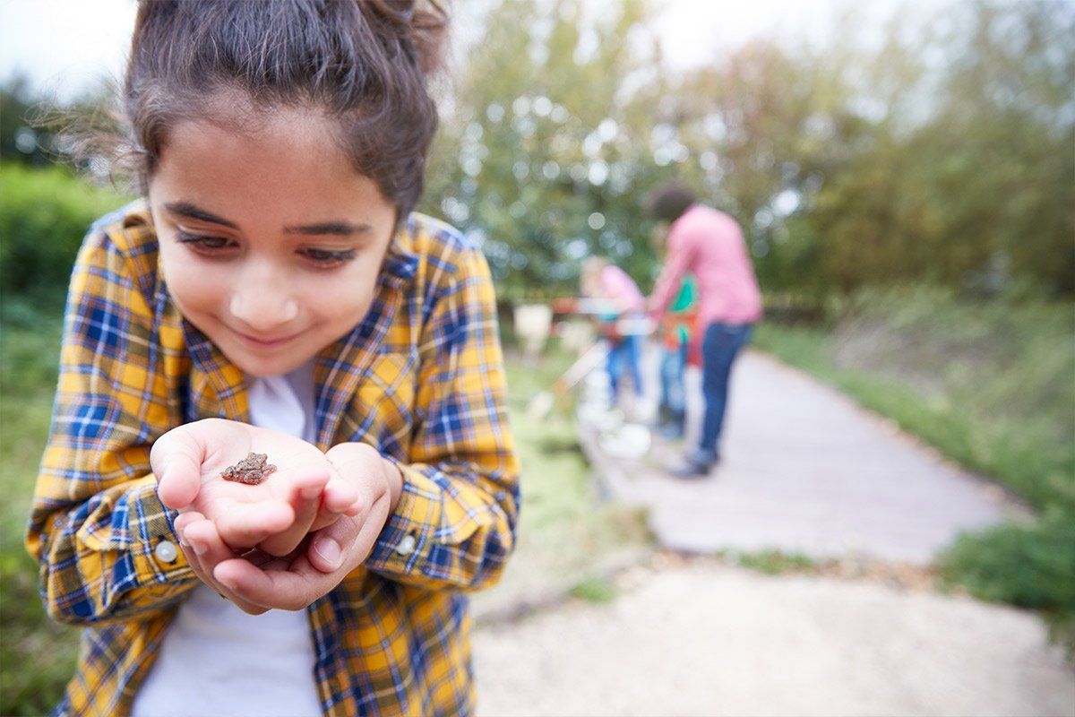 Jeune fille tenant dans sa main une petite grenouille