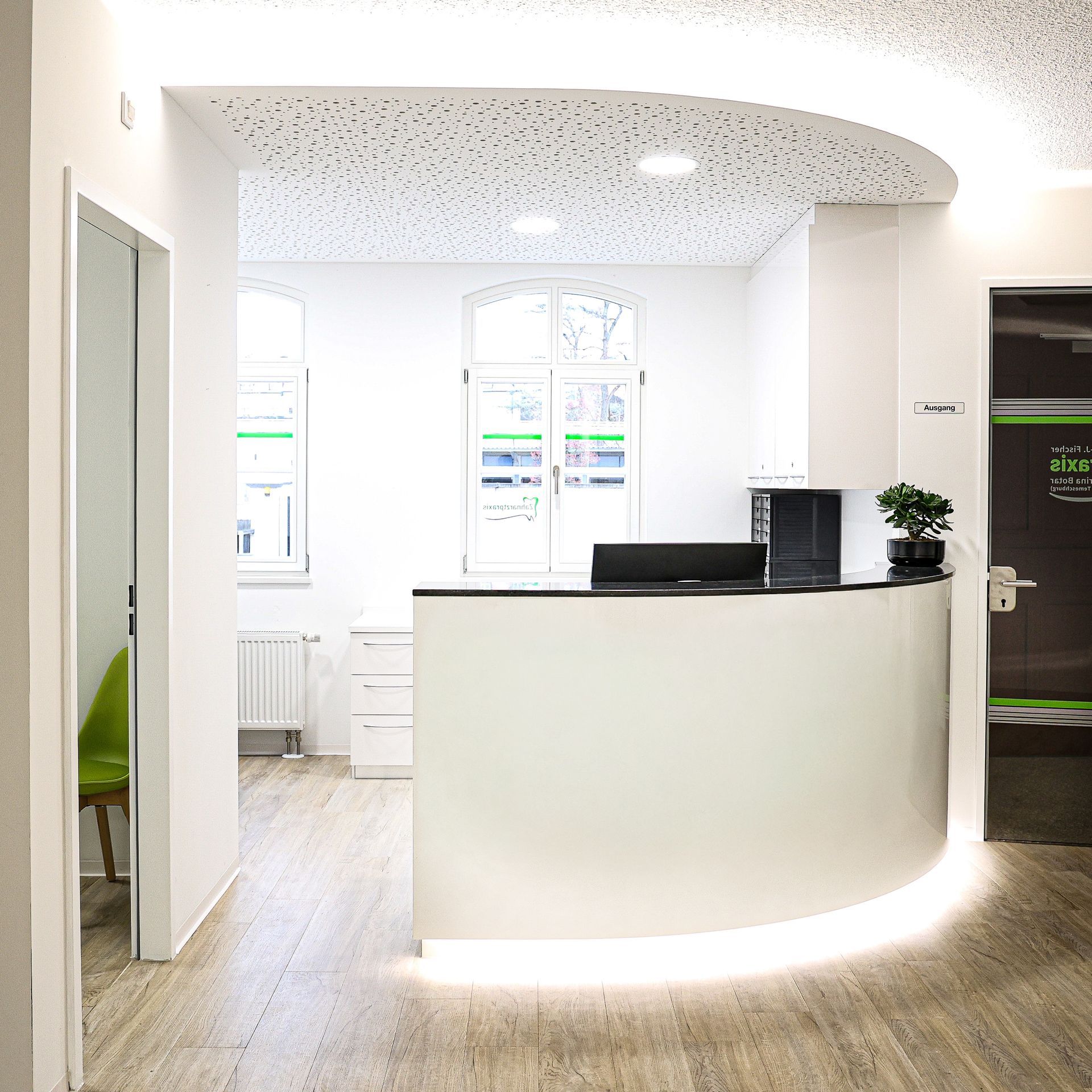 Empfangsbereich mit geschwungenem weißen Schreibtisch, minimalistischem Design und heller Beleuchtung.