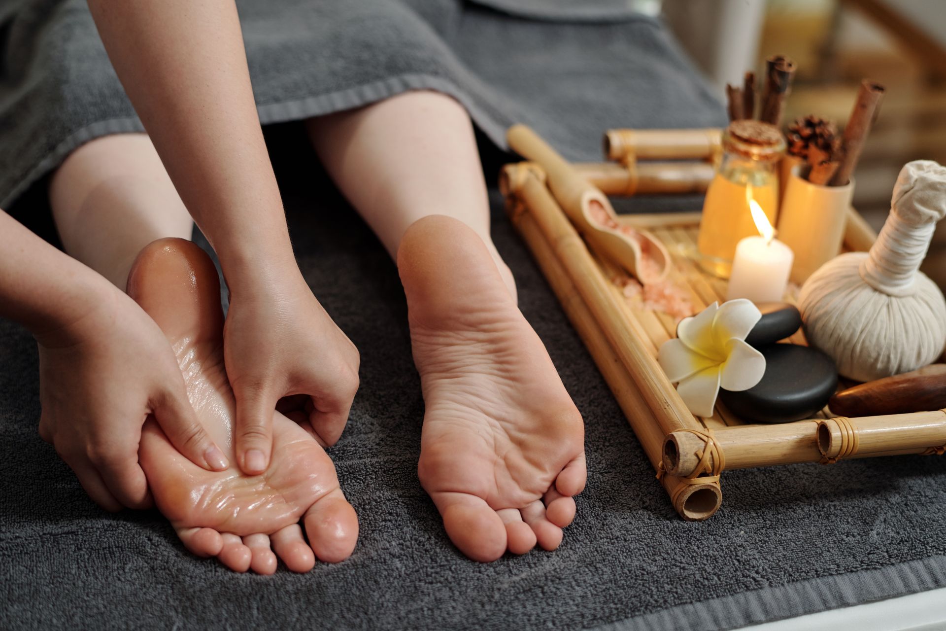Pieds trempant dans un décor de pédicure spa avec bougies, serviettes et outils de massage.