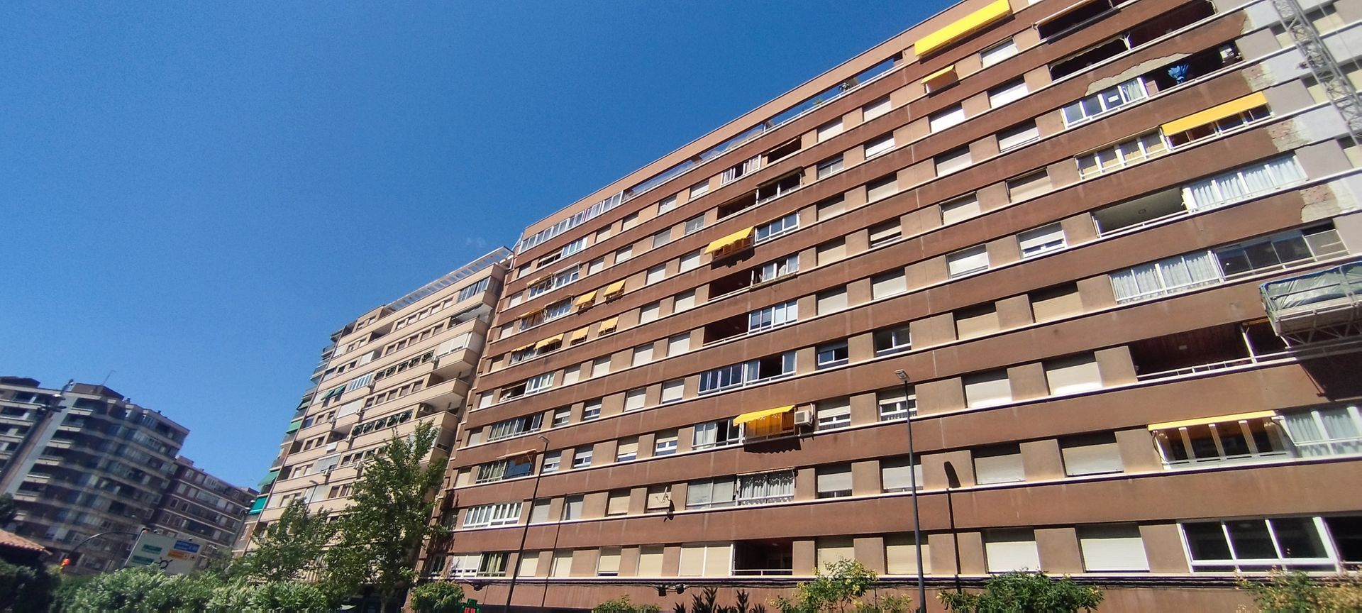 Un frente de tienda con una persiana en la puerta y un cartel en el costado del edificio.