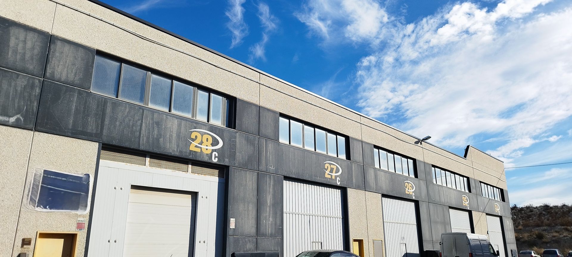 Un frente de tienda con una persiana en la puerta y un cartel en el costado del edificio.